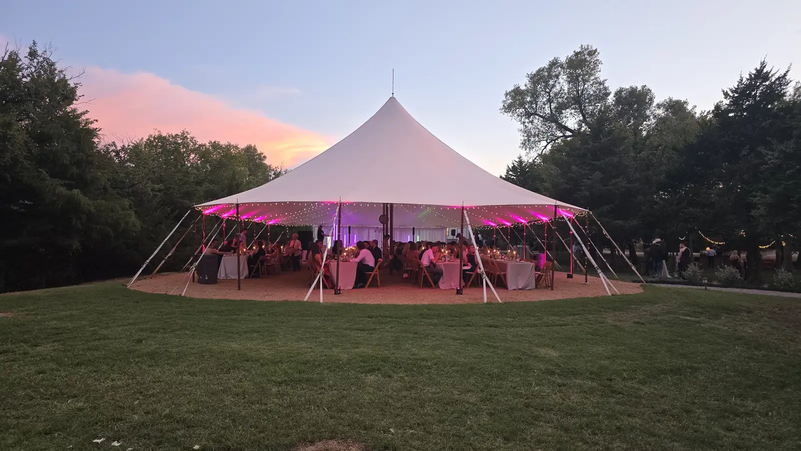A pole tent glowing pink at dusk