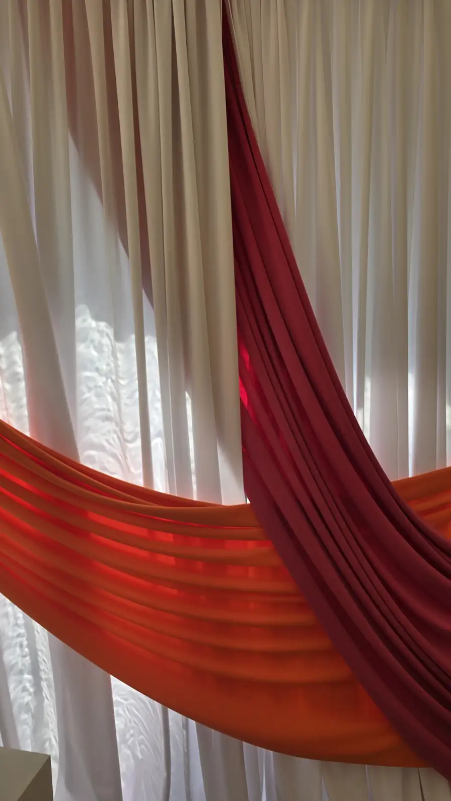 Red and orange accent swags sweeping across a sheer white backdrop