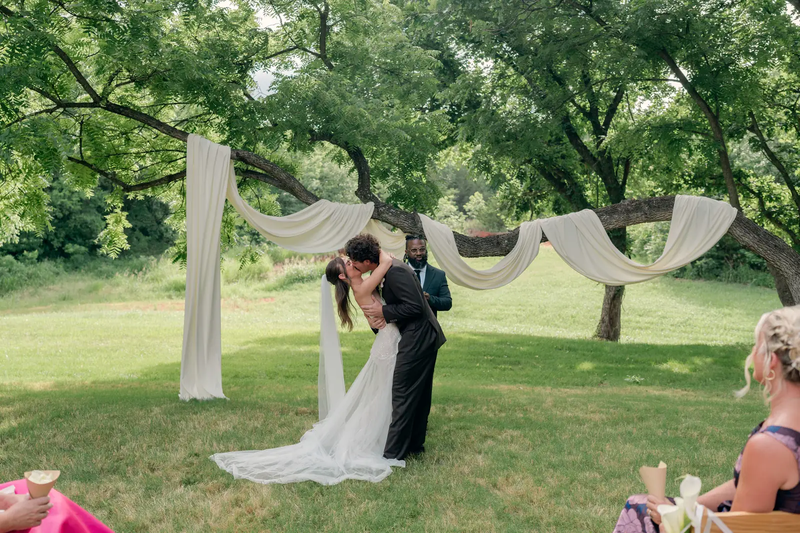 Rylee and Austin kiss at the altar under ivory tree swags